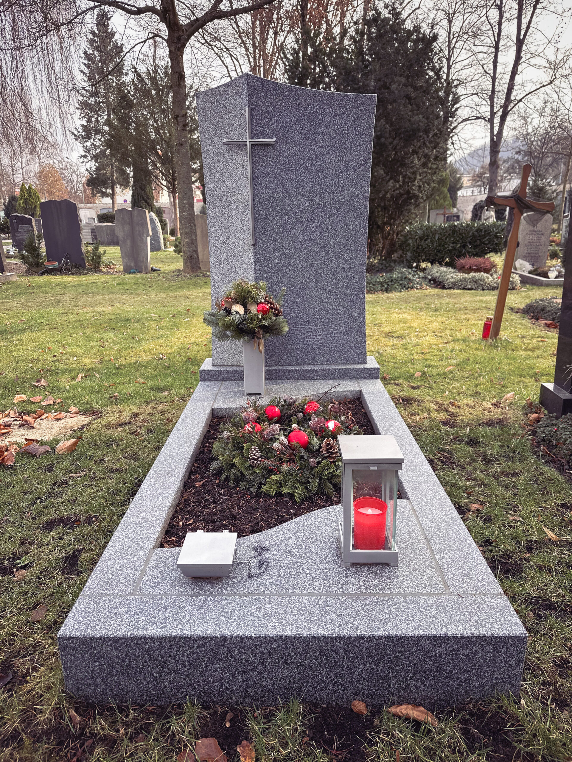 Granit-Grabmal mit Kreuz und winterlichem Grabschmuck mit Adventskranz