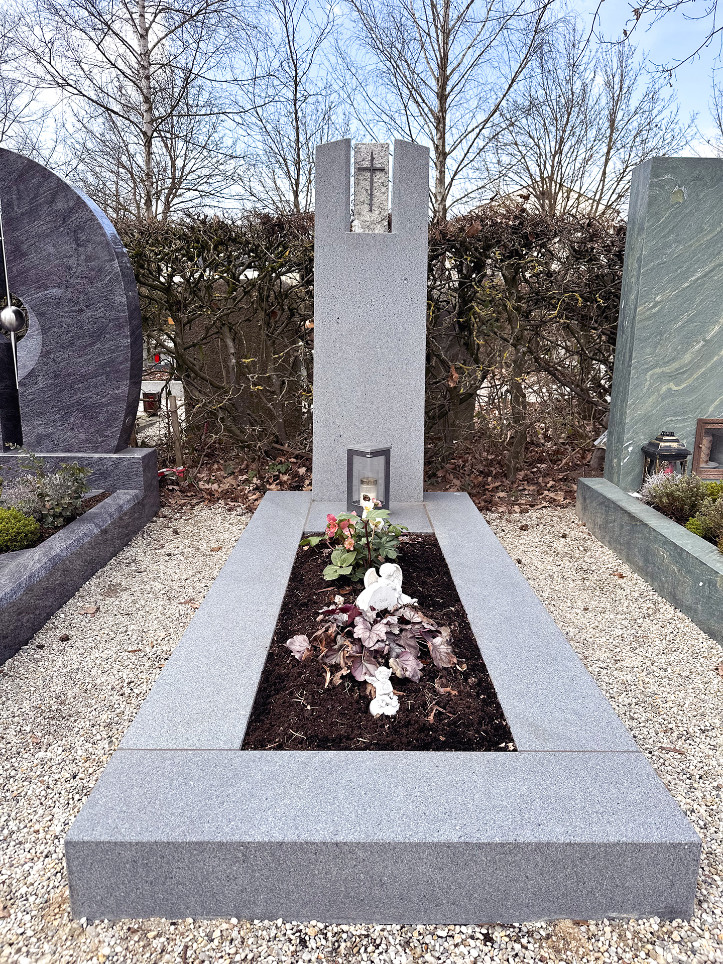 Granit-Grabmal mit kleinem Kreuz und herbstlicher Bepflanzung