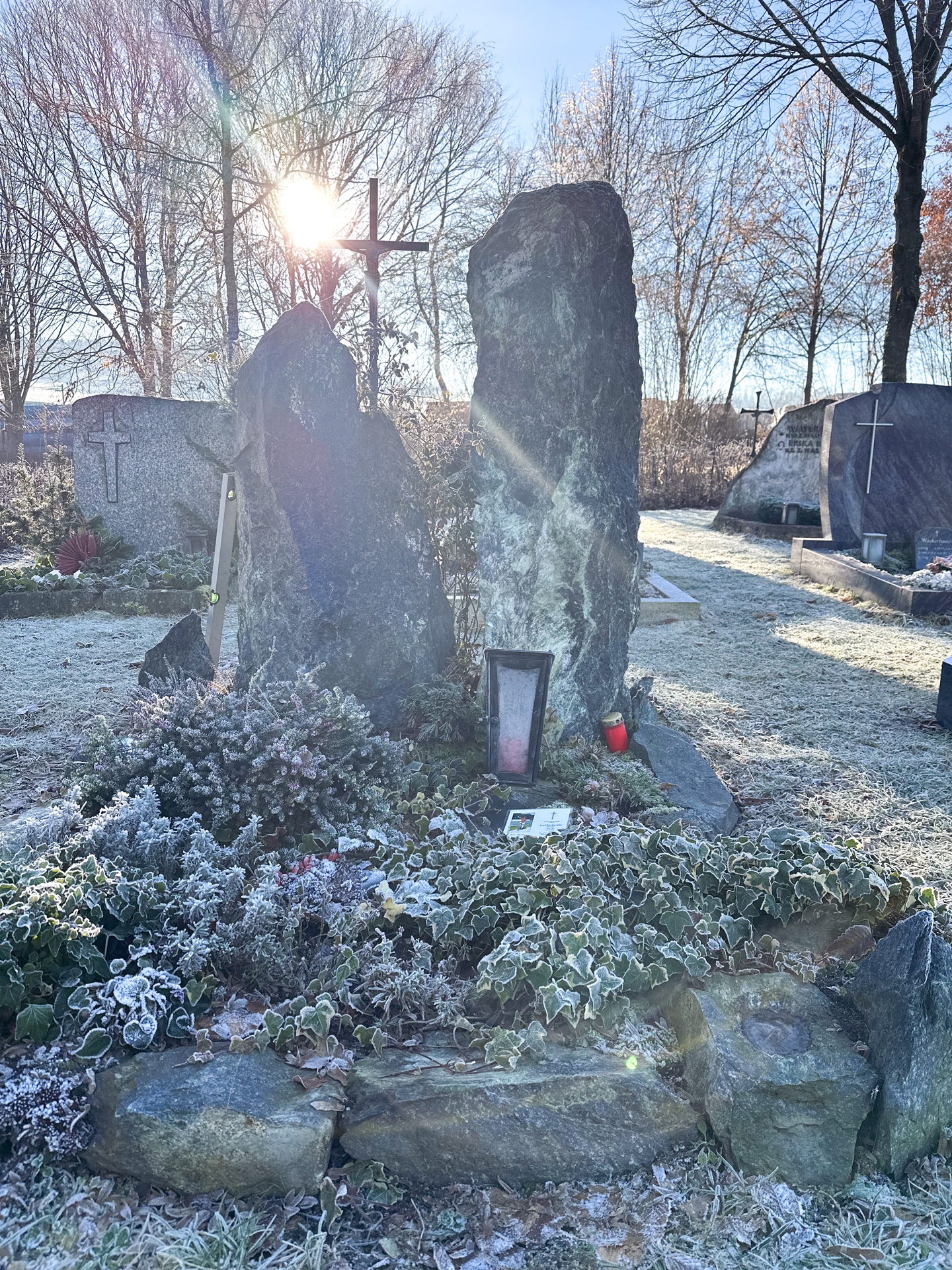 Zwei naturbelassene Findlings-Grabsteine mit Kreuz an einem frostigen Wintermorgen