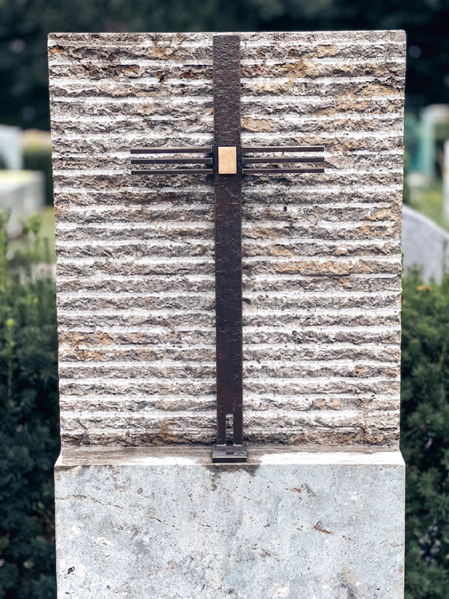 Grabmal aus gebändertem Naturstein mit schmiedeeisernem Kreuz