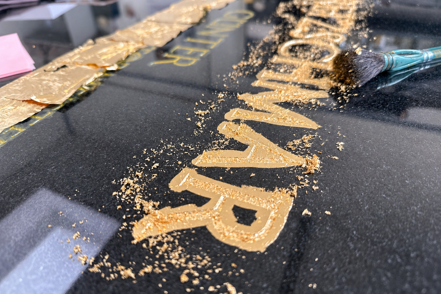 Vergoldung einer eingravierten Inschrift auf einem schwarzen Grabstein mit Blattgold