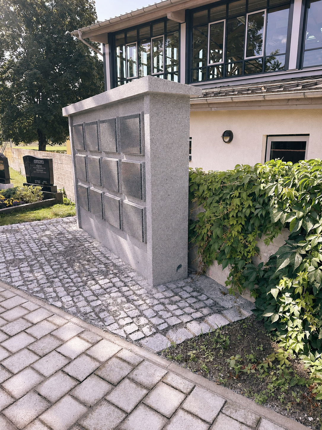 Granit-Urnenwand mit Namenstafeln neben einem Gebäude