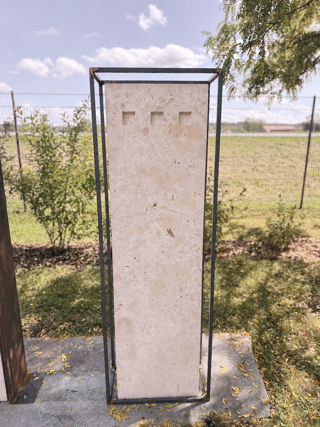 Helle Natursteintafel in einem Metallrahmen als Grabmal-Entwurf