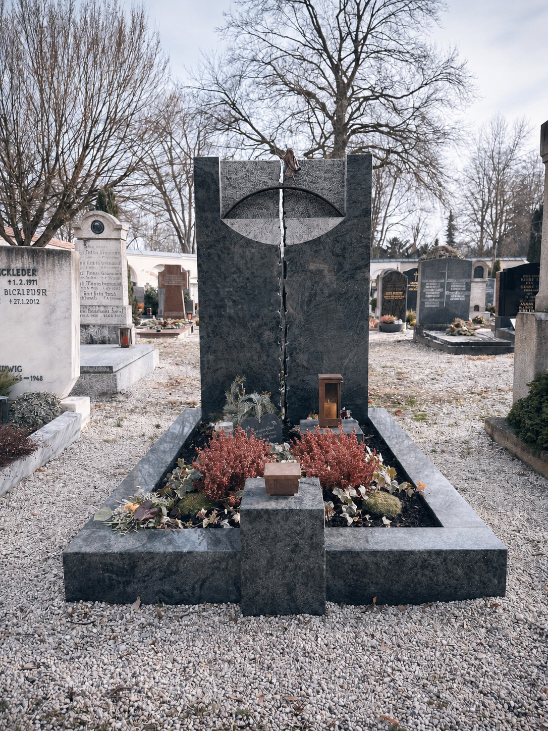 Dunkles Granit-Grabmal mit kreisförmigem Relief und Kreuz